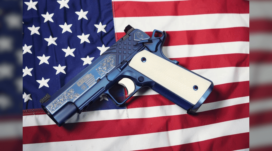 SK Guns 250 Years of Freedom 1911 Commander .45 ACP limited-edition pistol with sapphire PVD finish and patriotic custom engravings honoring America's 250th anniversary in front of american flag.