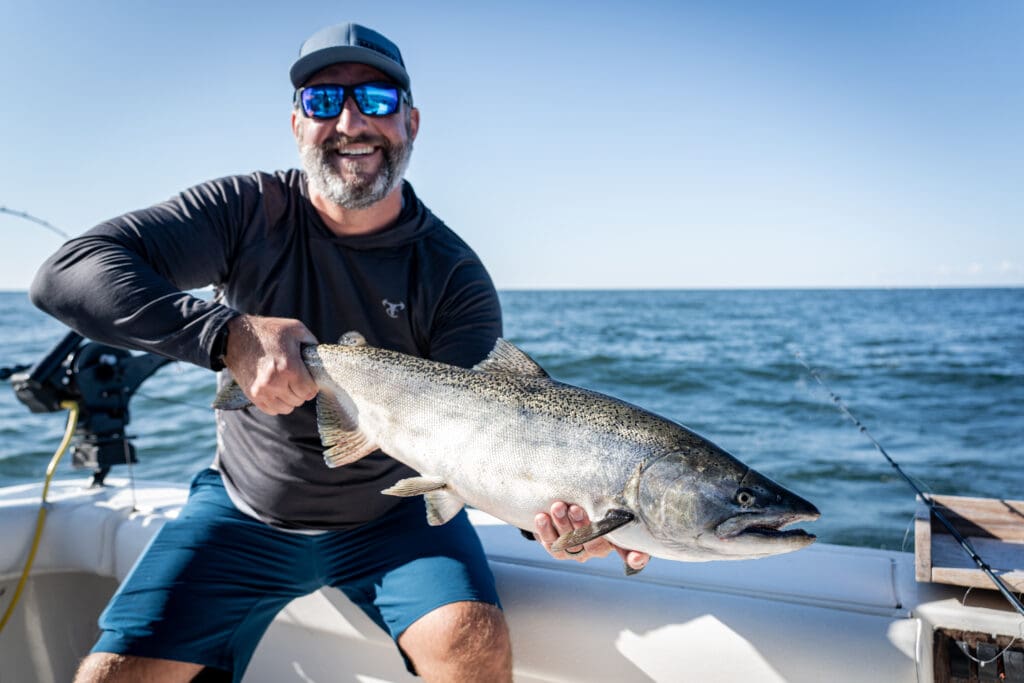 man in boat with big fish showing it off on the ocean