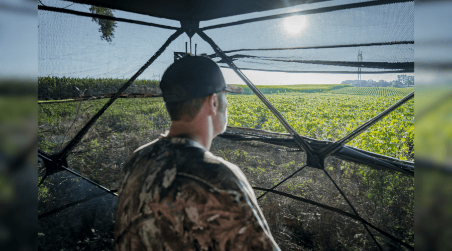 TrueTimber and Rugged Cross Hunting Blind with a person in it looking at field. See through hunting blind.